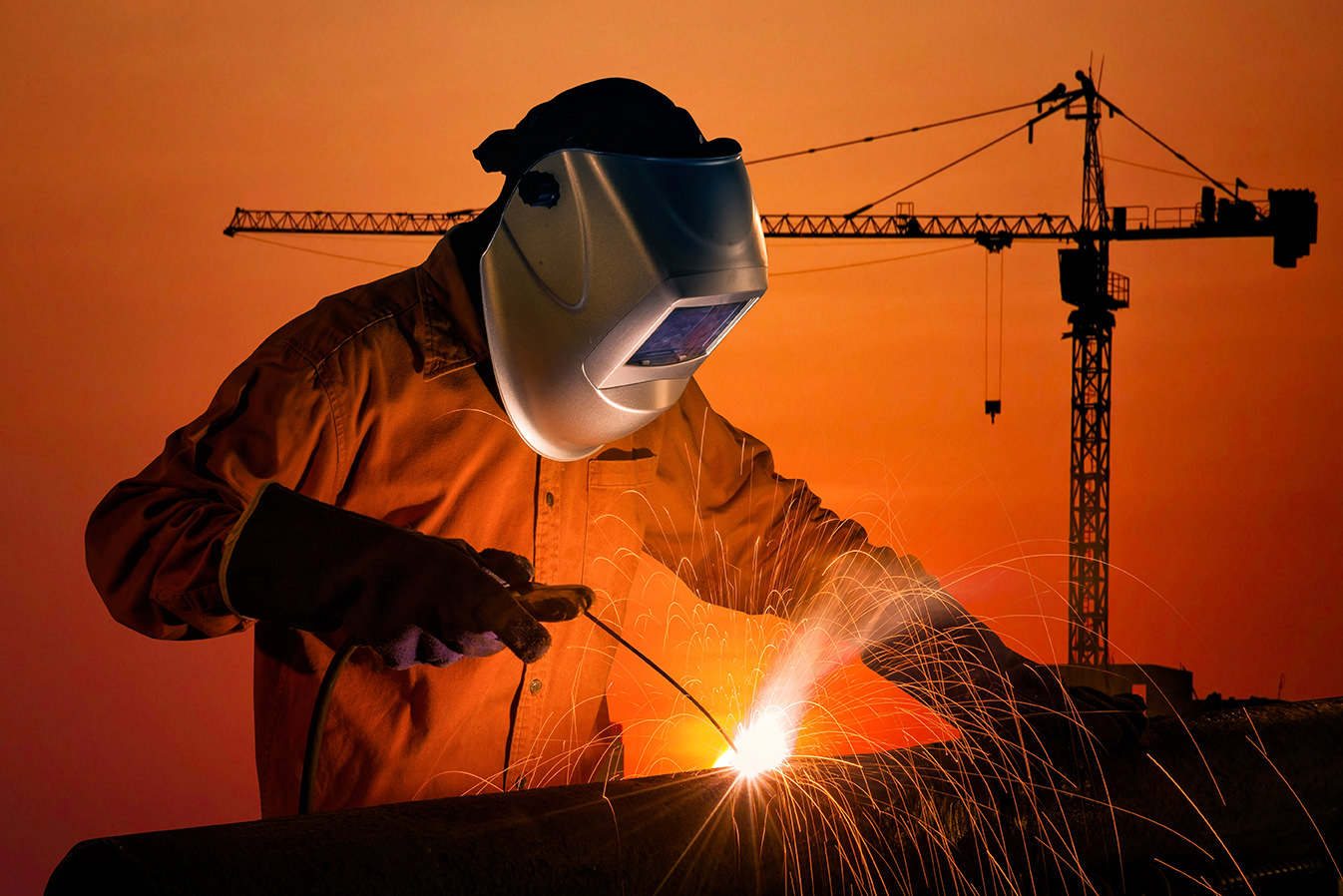 Welding worker welding steel structure with construction crane a